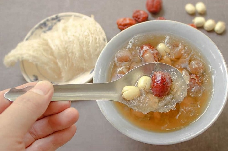 Chén chè yến với táo đỏ, hạt sen và sợi yến, tạo nên món tráng miệng bổ dưỡng và thơm ngon.