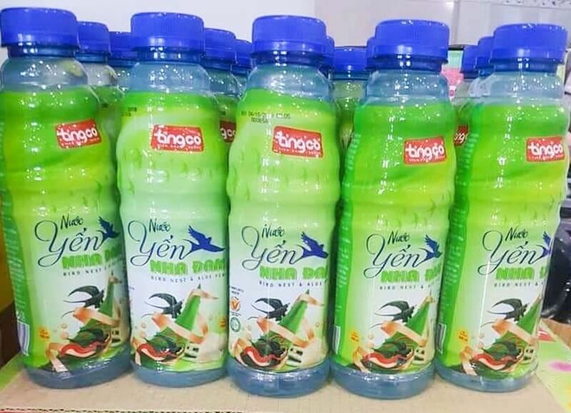 Chai nước yến nha đam nhãn hiệu Thiên Cơ, màu xanh lá cây, nắp xanh dương, xếp thành hàng trên kệ.