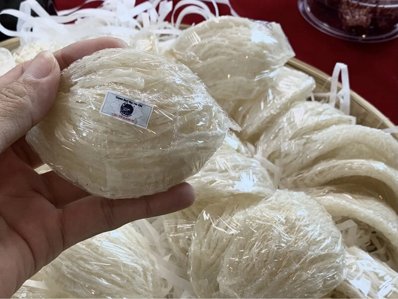 Người cầm tổ yến đã đóng gói trong tay, xung quanh là nhiều tổ yến khác trong giỏ, sẵn sàng để bán.