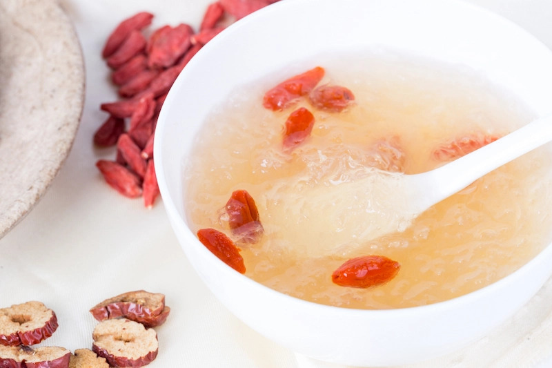 Chén súp tổ yến với kỷ tử và táo tàu, món ăn bổ dưỡng trong ẩm thực truyền thống, chụp gần trên nền sáng.