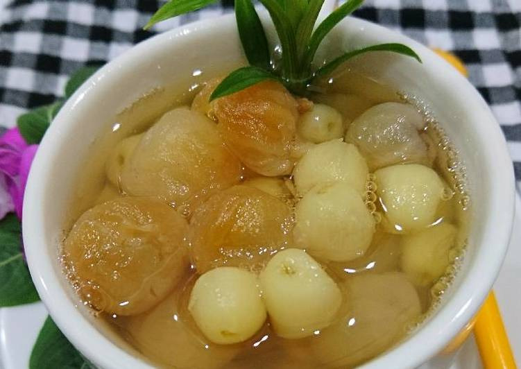 Chè hạt sen nhãn nhục trong bát trắng, trang trí lá xanh, nền bàn kẻ caro, món tráng miệng thanh mát và bổ dưỡng.