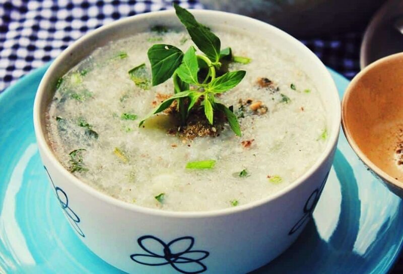 Bát cháo trắng được trang trí với rau thơm xanh tươi, đặt trên đĩa màu xanh, tạo cảm giác ngon miệng và hấp dẫn.
