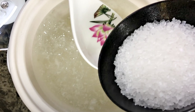 Bát chứa bột sắn dây trắng đang được đổ vào nồi nước sôi, chuẩn bị cho món ăn hoặc thức uống truyền thống.