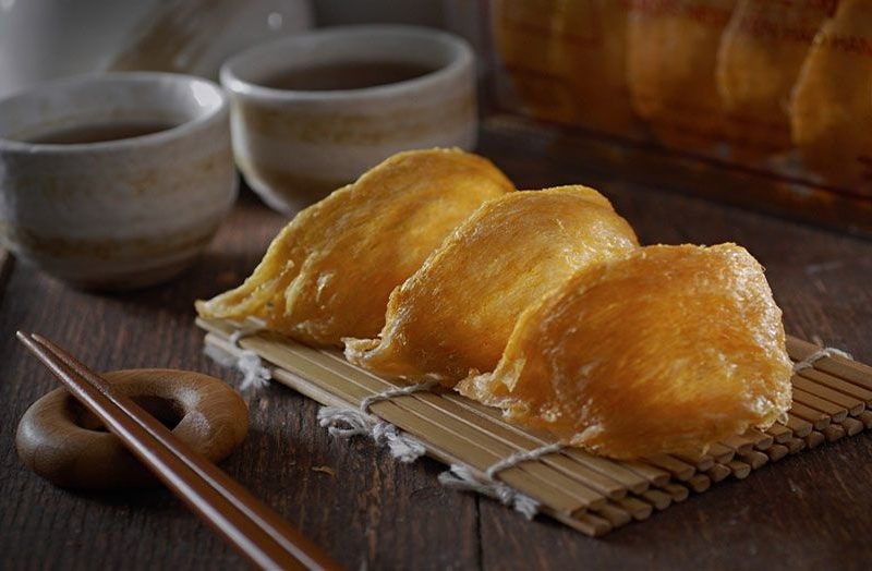 Tổ yến vàng sánh mịn trên tấm tre, bên cạnh là hai tách trà gốm, tạo nên không gian ẩm thực sang trọng.