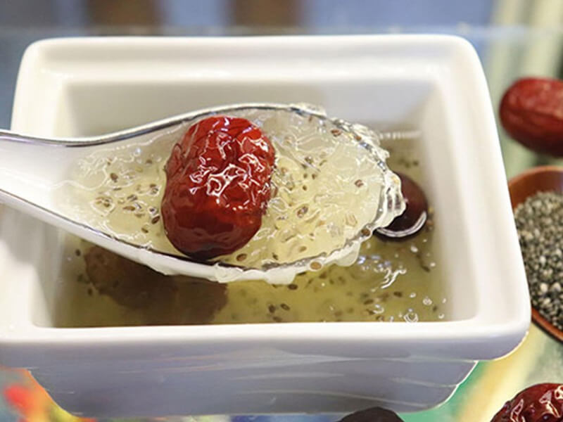 Món chè hạt é thanh mát với táo đỏ trong bát sứ trắng, tạo nên hương vị ngọt ngào và hấp dẫn, thích hợp cho ngày hè.