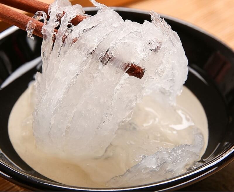 Món thạch sương sáo trong bát đen, được gắp lên bằng đũa, tạo cảm giác mát lạnh và hấp dẫn cho mùa hè.